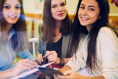İş ortaklarının birlikte çalışma alanında buluşurken kameraya baktıkları pozitiflik portresi, atölyede birlikte çalışmaktan zevk alan mutlu beyaz kadınlar.