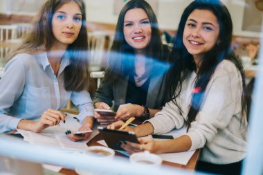 Neşeli kadın partnerlerin portresi, tanıtım alanında elinde modern aletlerle oturan ve işbirliği sırasında gülümseyen, teknoloji kullanan mutlu kadınların portresi.