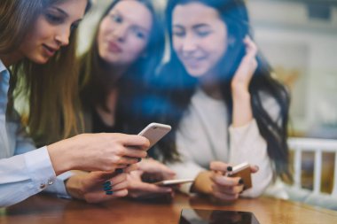 Profili güncellemek için cep telefonlarında 4G kablosuz bağlantı kullanan çekici hippi kızlar, tanıtım alanında boş zamanlarında içerik siteleri hakkında bilgi arayan genç kadınlar