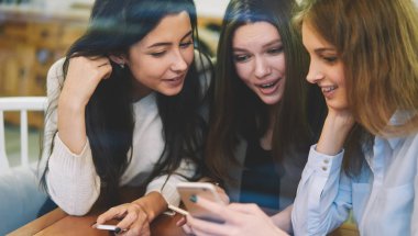 Wi-fi bölgesinde birlikte zaman geçirirken akıllı telefon uygulaması üzerinden sevimli medya dosyalarını izleyen neşeli refah kadınları, cep telefonuyla olumlu e-postalar okuyan mutlu hippi kızlar.