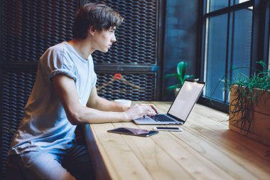 Kafkas erkek metin yazarı dizüstü bilgisayarla uzaktan çalışıyor web sitesi için yeni içerik makalesi hazırlıyor, kafeterya masasında oturan ve Netbook 'ta yazılım ve antivirüs uygulamalarını güncelliyor