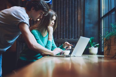 Beyaz erkek ve kadın serbest çalışanlar dizüstü bilgisayarda birlikte çalışıyorlar uygulama ayarları içinde veri düzenliyorlar, bin yıllık yetenekli hipsterler içerik web siteleri hakkında bilgi arıyorlar