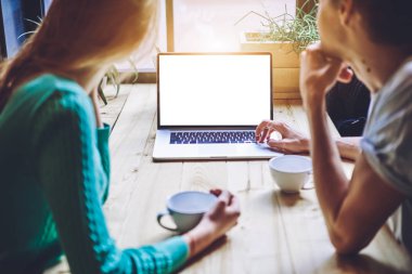 Romantik film arayan genç çiftin arka planında, kafeteryada boş zamanlarında çevrimiçi izlemek için, erkek ve kadın dizüstü bilgisayarla internete bakıyorlar ve web siteniz için ekran oluşturuyorlar.