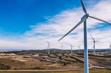 Kuşlar rüzgar enerjisinden yeşil enerji kaynakları üreten yel değirmenleri istasyonunu tarımın engin alanlarında görüyorlar. Çayırlarda dönen türbinlerle alternatif elektrik üretimi