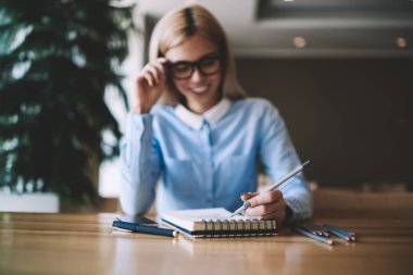 Eğitim için ders kitabında okul ödevleri ve çizim tasarım skeçler yapıyor kadın el seçici odak, sınıf odasında ahşap masada otururken sınava hazırlanıyor zevk mutlu kadın öğrenci