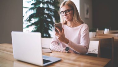 Gözler ekran akıllı telefon dokunmatik ekranı kontrol sağlamak için gözlükler başarılı hipster kız, arkadaşlar ile iletişim için modern mobil ve dizüstü cihazlar kullanarak giyinmiş pozitif kadın Casual