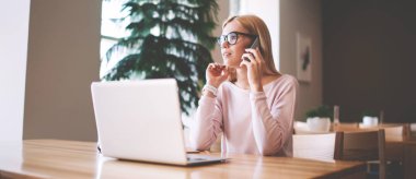 Ciddi kadın programcı dizüstü bilgisayar için sağlayıcı tedarikçisi hakkında Müşteri Hizmetleri ile tebliğ, iş arkadaşı ile önemli akıllı telefon görüşmesi yapma gözlükler konsantre kadın
