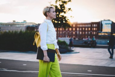 Moda sırt çantası ve eğitim ders kitabı ile şık genç kadın ücretsiz akşam zamanında modern kasabanın cadde boyunca yürüyüş, kentsel ortamda Notepad gezinme ile beyaz kadın öğrenci