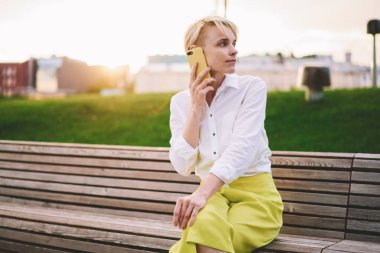 Millennial hipster kız Casual Look içinde müşteri hizmetleri ile ciddi uluslararası konuşma yapmak giyinmiş modern akıllı telefon cihazı kullanarak dolaşım 4g internet bağlantısı hakkında danışmanlık