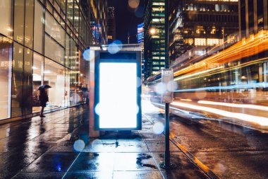 Reklam veya promosyon içeriği için boş kopya boşluk ekranı ile yağmurlu gece otobüs terminali Billboard, bilgi için lightbox kadar boş sahte, uzun pozlama ile kentsel şehir sokakta boş ekran