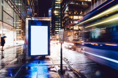 Reklam veya promosyon içeriği için boş kopya boşluk ekranı ile yağmurlu gece otobüs terminali Billboard, bilgi için lightbox kadar boş sahte, uzun pozlama ile kentsel şehir sokakta boş ekran