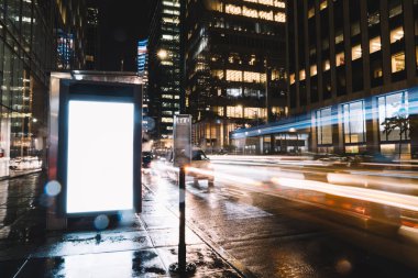 Reklam veya promosyon içeriği için boş kopya boşluk ekranı ile yağmurlu gece otobüs terminali Billboard, bilgi için lightbox kadar boş sahte, uzun pozlama ile kentsel şehir sokakta boş ekran