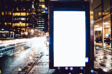 Reklam veya promosyon içeriği için boş kopya boşluk ekranı ile yağmurlu gece otobüs terminali Billboard, bilgi için lightbox kadar boş sahte, uzun pozlama ile kentsel şehir sokakta boş ekran