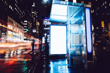 Reklam veya promosyon içeriği için boş kopya boşluk ekranı ile yağmurlu gece otobüs terminali Billboard, bilgi için lightbox kadar boş sahte, uzun pozlama ile kentsel şehir sokakta boş ekran