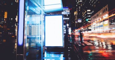 Reklam veya promosyon içeriği için boş kopya boşluk ekranı ile yağmurlu gece otobüs terminali Billboard, bilgi için lightbox kadar boş sahte, uzun pozlama ile kentsel şehir sokakta boş ekran