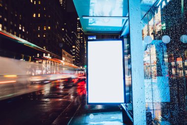 Reklam veya promosyon içeriği için boş kopya boşluk ekranı ile yağmurlu gece otobüs terminali Billboard, bilgi için lightbox kadar boş sahte, uzun pozlama ile kentsel şehir sokakta boş ekran