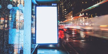Reklam veya promosyon içeriği için boş kopya boşluk ekranı ile yağmurlu gece otobüs terminali Billboard, bilgi için lightbox kadar boş sahte, uzun pozlama ile kentsel şehir sokakta boş ekran