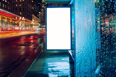 Reklam veya promosyon içeriği için boş kopya boşluk ekranı ile yağmurlu gece otobüs terminali Billboard, bilgi için lightbox kadar boş sahte, uzun pozlama ile kentsel şehir sokakta boş ekran