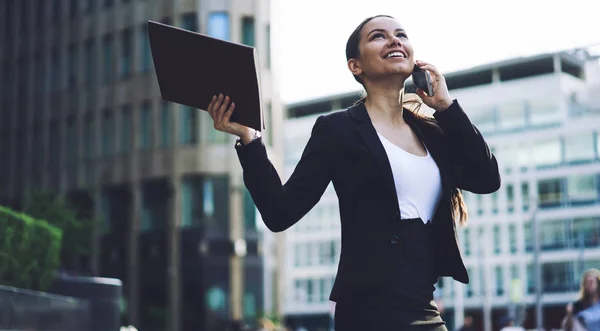 Overjoyed smiling female entrepreneur in corporate skirt suit feeling excited after making good deal with business partners calling via cellphone. Business woman celebrating achievement after get job