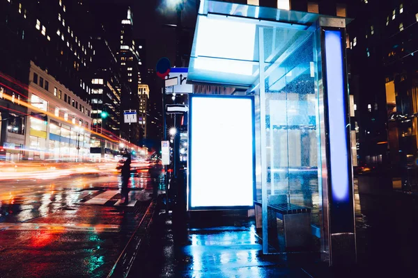 広告やプロモーションコンテンツのための空白のコピースペース画面 情報のための空白のモックアップライトボックス 長時間露光を持つ都市部の通りに空白の表示と雨の夜のバスステーションの看板 — ストック写真
