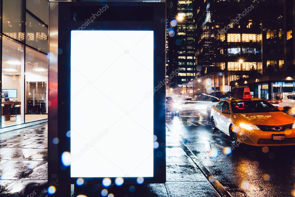 Bus station billboard in rainy night with blank copy space screen for advertising or promotional content, empty mock up Lightbox for information, blank display in urban city street with long exposure