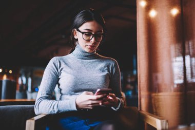 Çekici trendy hipster kız göz giyim tutan cep telefonu sırasında bloglama ve tarama internet kafeteryada kapalı oturma, modern teknoloji kavramı sosyal ağlar iletişim