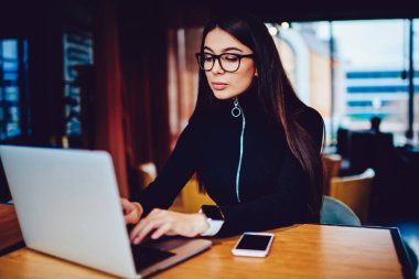 Yetenekli genç kadın yazılım geliştiricisi dizüstü bilgisayar üzerinden göz koruma çalışma sağlamak için gözlükler içinde WiFi Kapalı, trendy akıllı hipster kız bağlı Netbook yeni antivirüs yükleme