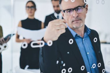 Şirkette çalışırken göz koruma amaçlı yazma organizasyonu planı sağlamak için optik gözlük takan konsantre olmuş yetişkin iş adamı ciddi bir erkek yönetmen verimli bir strateji yaratıyor.