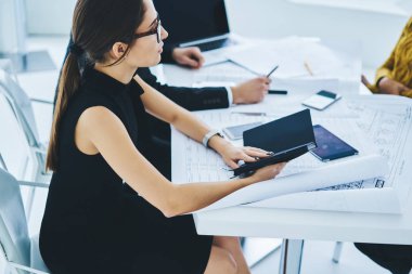 Ciddi iş kadını göz göze gelmiş, ders kitabı elinde iş arkadaşlarıyla oturuyor ve takas planlama toplantısı düzenliyor, bir grup zeki girişimci çalışma alanındaki yönetim projesini tartışıyor.