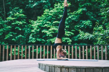 Sarvangasana sabah yoga ayakta ve sağlıklı yaşam tarzı zevk için Sportive kadın atlet harcama zamanı, Genç ince kadın doğa ortamında eğitim için mat omuz standı yapıyor