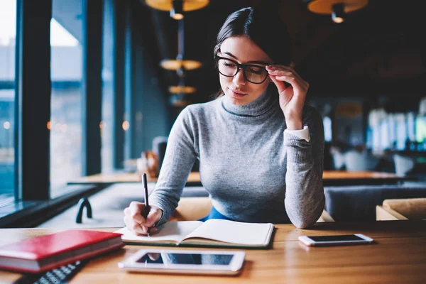 Konzentrierte Ernsthafte Studentin Sitzt Holztisch Mit Stylischer Brille Und Schreibt — Stockfoto