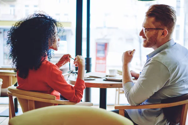 成功した暗い肌の起業家がコーヒーショップでのビジネスミーティング中に白人経験豊富なマネージャーと話し合い 多文化の所有者が協力計画を議論するバックビュー — ストック写真