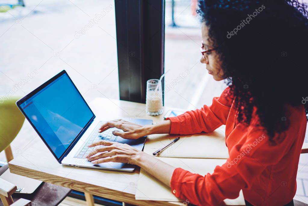 Black female freelancer typing text in laptop application while creating new chapter of book, afro american woman updating antivirus app on modern netbook, concept of technology and communication