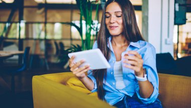 Modern cihazlar aracılığıyla içerik sitesinde bulunan komik videolardan gülen mutlu kadın. Gündüz rahat iç mekanlarda pozitif haber okumak için ücretsiz kablosuz bağlantı kullanan başarılı kadın.