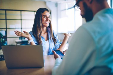 Yüz üzerinde şok duygu ile erkek arkadaşı ile sosyalleşmek mutlu hayran hipster kız, Açık Laptop ile masaüstünde oturan başlangıç projesi için serin fikirler hakkında adam ile konuşan merak beyaz kadın