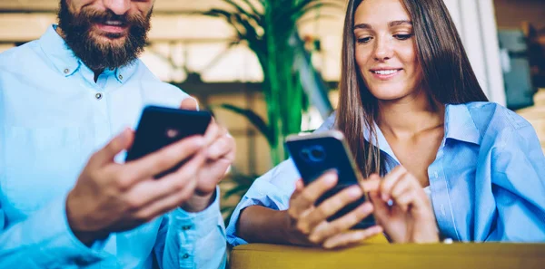 Happy male and female holding smartphone devices and messaging with friends ignoring live communication, man and woman using digital gadgets for updating profiles in social networks during free time