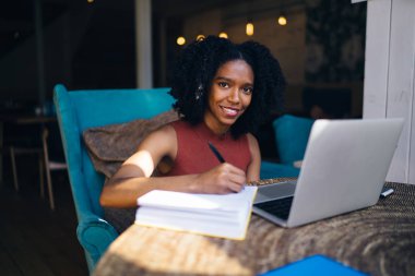 Loft iç otodidakt için zaman içinde kamera gülümseyen karanlık cilt ile mutlu kadın öğrenci portresi, neşeli Afrikalı Amerikalı kadın e öğrenme ve hazırlık ders çalışması için zevk