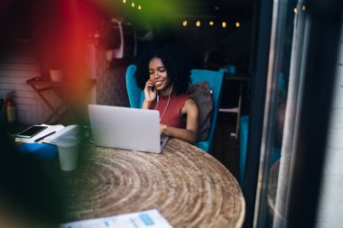 Modern netbook üzerinde 4g internet kullanarak arkadaşlarınızla olumlu video konferansı zevk elektronik kulaklıklar neşeli koyu tenli kadın, Web sayfasında komik video izlerken mutlu hipster kız