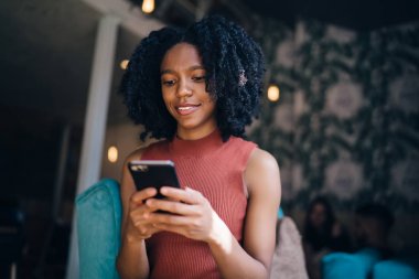 Cep telefonu WiFi internet bağlı arkadaşınıza göndermek için metin mesajı yazarak pozitif siyah hipster kız, mutlu kadın genç boş zaman içinde cep telefonu online oyun oynarken