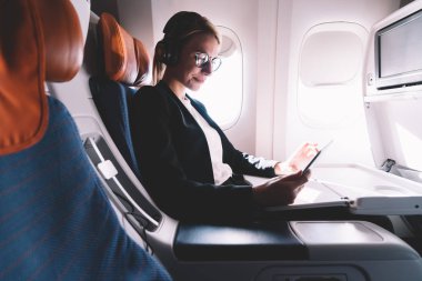 Gemide WiFi bağlı Kıtalararası uçuş sırasında sosyal ağda vizyon düzeltme okuma metin yayınları için gözlük pozitif beyaz kadın, mutlu kadın tarama web siteleri