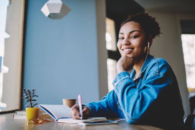 Çoklu görev ve zevk kavramı, neşeli Afro Amerikan meloman portre reklam alanında oturan ve yüksek hacimli elektronik kulaklıklar ile favori pozitif müzik çalma listesi dinleme