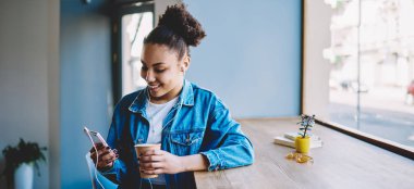 Neşeli bayan meloman grup sohbetinde arkadaşlarıyla sohbet ederken kendini iyi hissediyor. Müzik dinlemek için akıllı telefon uygulaması kullanıyor, cep telefonuyla gülümseyen hippi kız mesajlaşıyor.