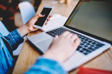 Elle cep telefonu tutan kadın el kırpılmış görüntü ve Bluetooth bağlantısı üzerinden dizüstü bilgisayar için metin dosyalarını paylaşan, modern netbook üzerinde program kodu oluşturmak profesyonel yetenekli