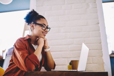 Görme düzeltmesi için optik gözlüklü mutlu siyah kadın sosyal ağlardaki ünlü blogcu profilini okuyor, içerik sitesinde pozitif film izleyen neşeli hippi kız