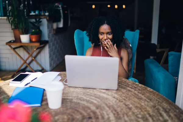 惊讶的黑皮肤女性博客感到兴奋 从收到良好的视频评论自己的网页在社交网络使用电子耳机听 在线多任务的概念 — 图库照片