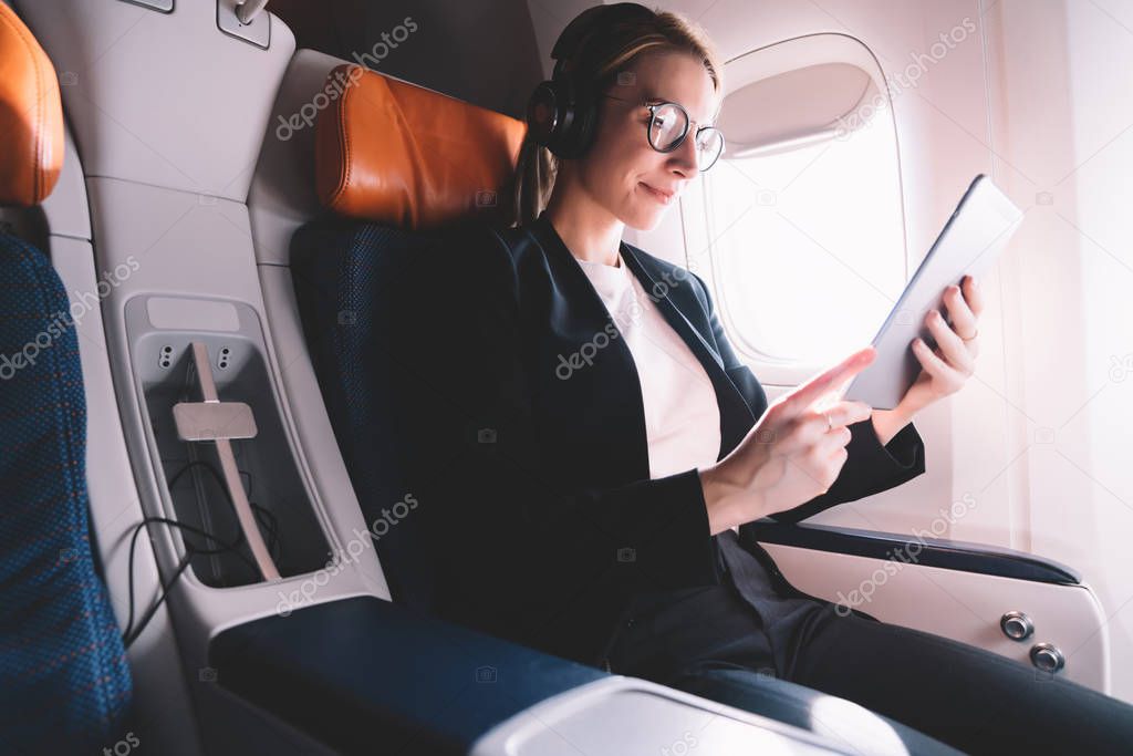 Caucasian woman traveler sitting in aircraft and using technology using wireless on board