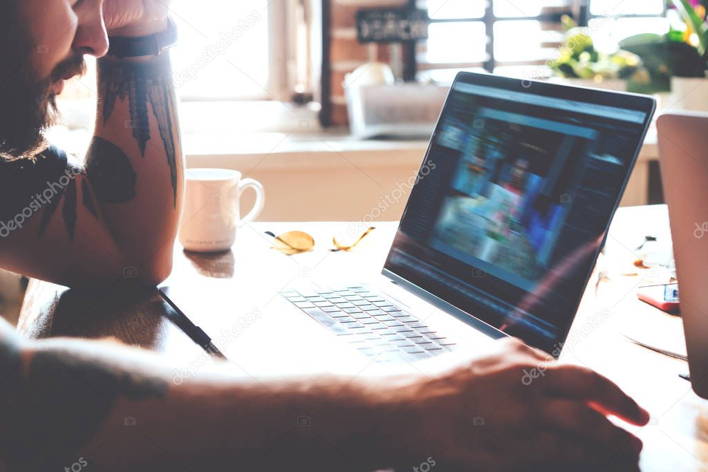 Cropped view of male using laptop computer with screen while sitting at wooden desktop table, male freelancer browse web page on netbook working remotely in interior, copy space area on display 