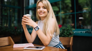 Açık kafede sıcak içki ile gülümseyen kadın