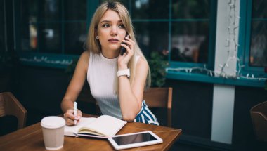 Akıllı Telefonda konuşan ve notlar yapma düşünceli Freelancer