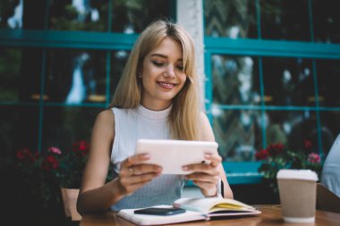 Cafe masasında tablet kullanarak gülümseyen kadın